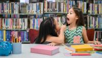 Two little happy cute girls making funny face and playing together in library at school as dental health check.